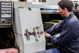 Machinist operating a Swiss CNC turning machine