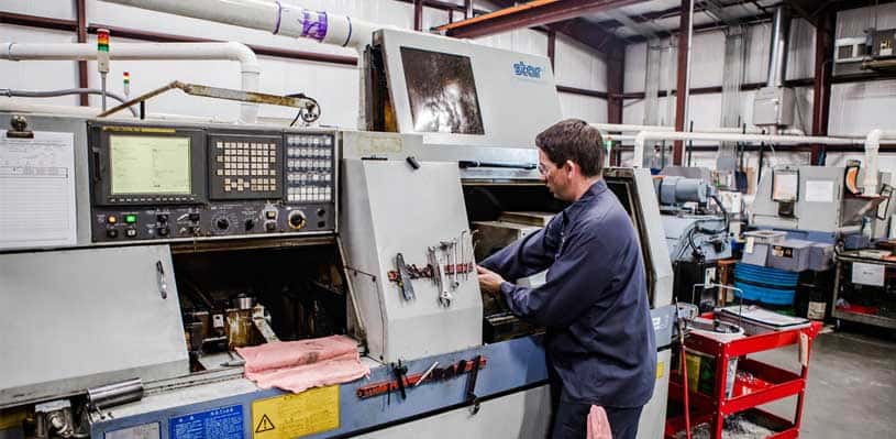 Machinist operating a Swiss CNC lathe